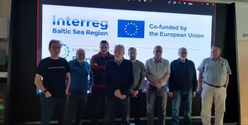 Eight persons standing in the front of office screen