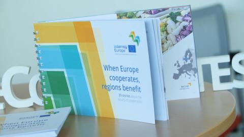 Publication entitled 'When Europe cooperates, regions benefit' placed upon a table with hashtag Europe cooperates behind it