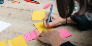 person writing on a post-it note