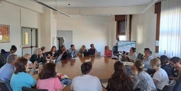 People sit in a room around a large table 